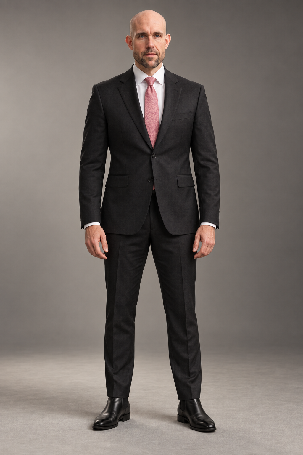 Jeremy wearing a tailored black suit and pink tie in a professional studio